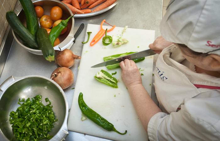 Pulsa para ver la imagen en grande: Cocinera picando verduras en una cocina de una escuela municipal infantil de Zaragoza